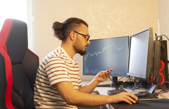 Crypto investor sits in gaming chair in home office and checks charts