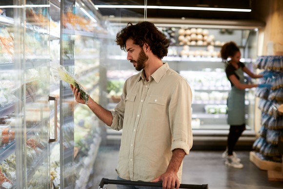 A person choosing products from a refrigerator case in a supermarket.