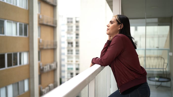 Person standing on a balcony and leaning on a railing.