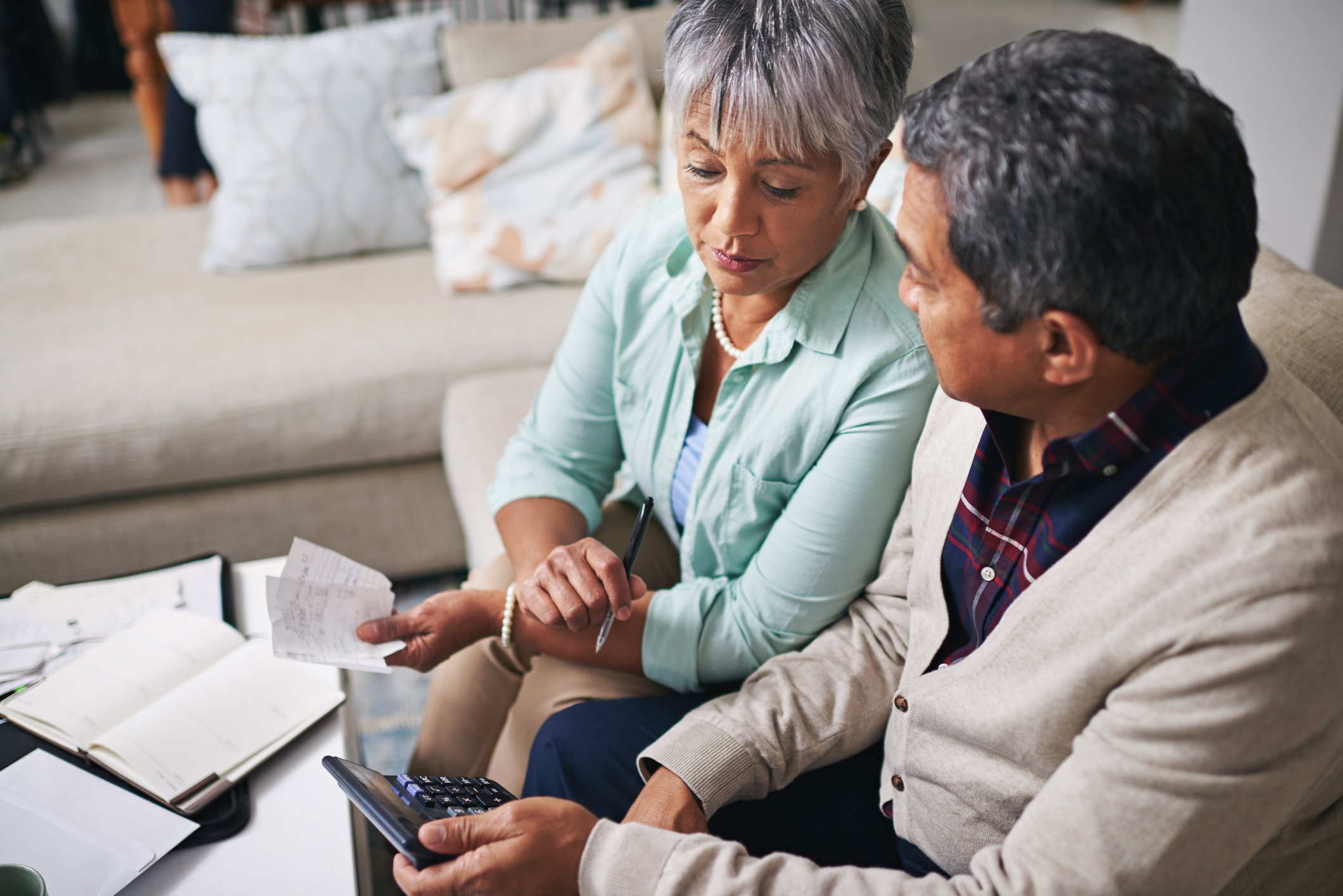 Two people looking at a calculator and receipts.