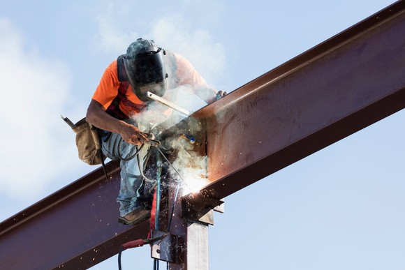 A welder works on a steel girder. 