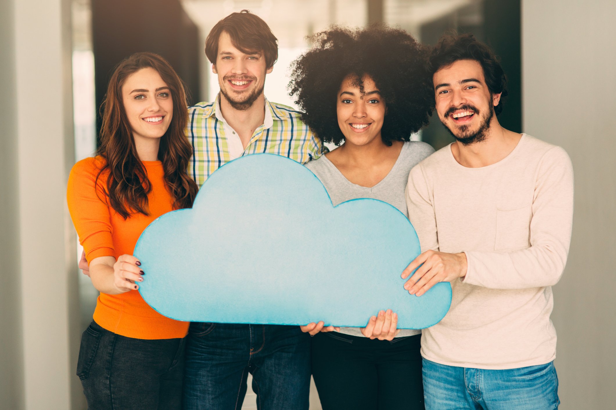 Four people are holding a cloud cutout.