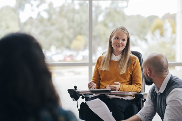 A person in a wheelchair presents at a business meeting.