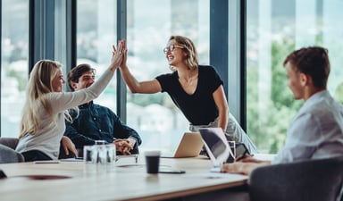 Two people at a desk giving a high five.