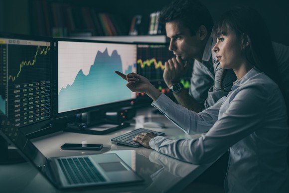 Two people looking at a line graph on a computer screen.