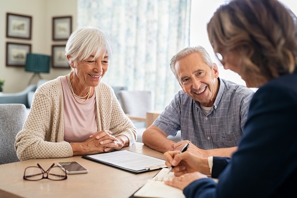 Three people are smiling while sitting at a table.