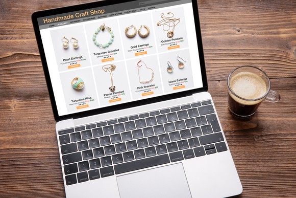 A laptop displaying a jewelry page, next to a cup of coffee.