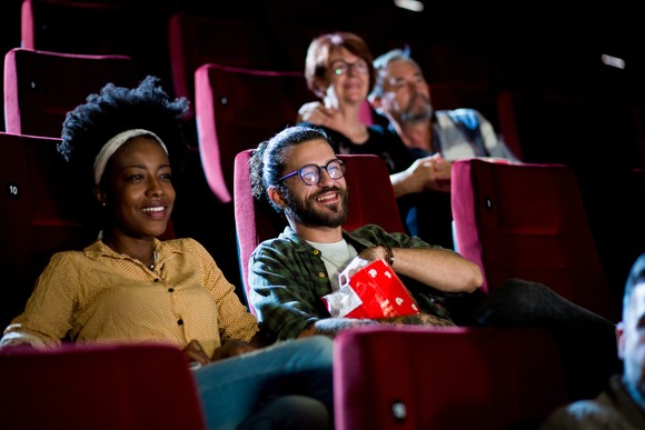 Two couples enjoying what they're seeing projected at a movie theater.