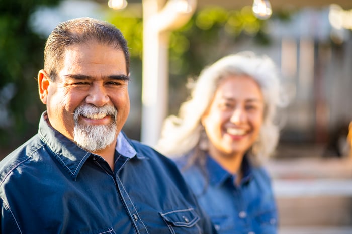 Two people standing outside and smiling.