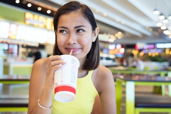 Customer drinking a fountain soda at mall food court.