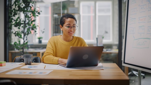 Someone sitting on a desk on a laptop.