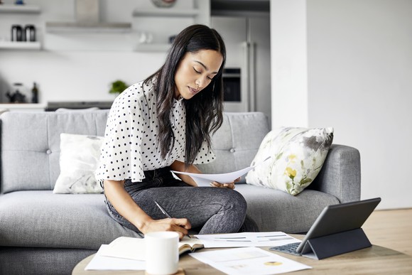A person works on documents at a coffee table.