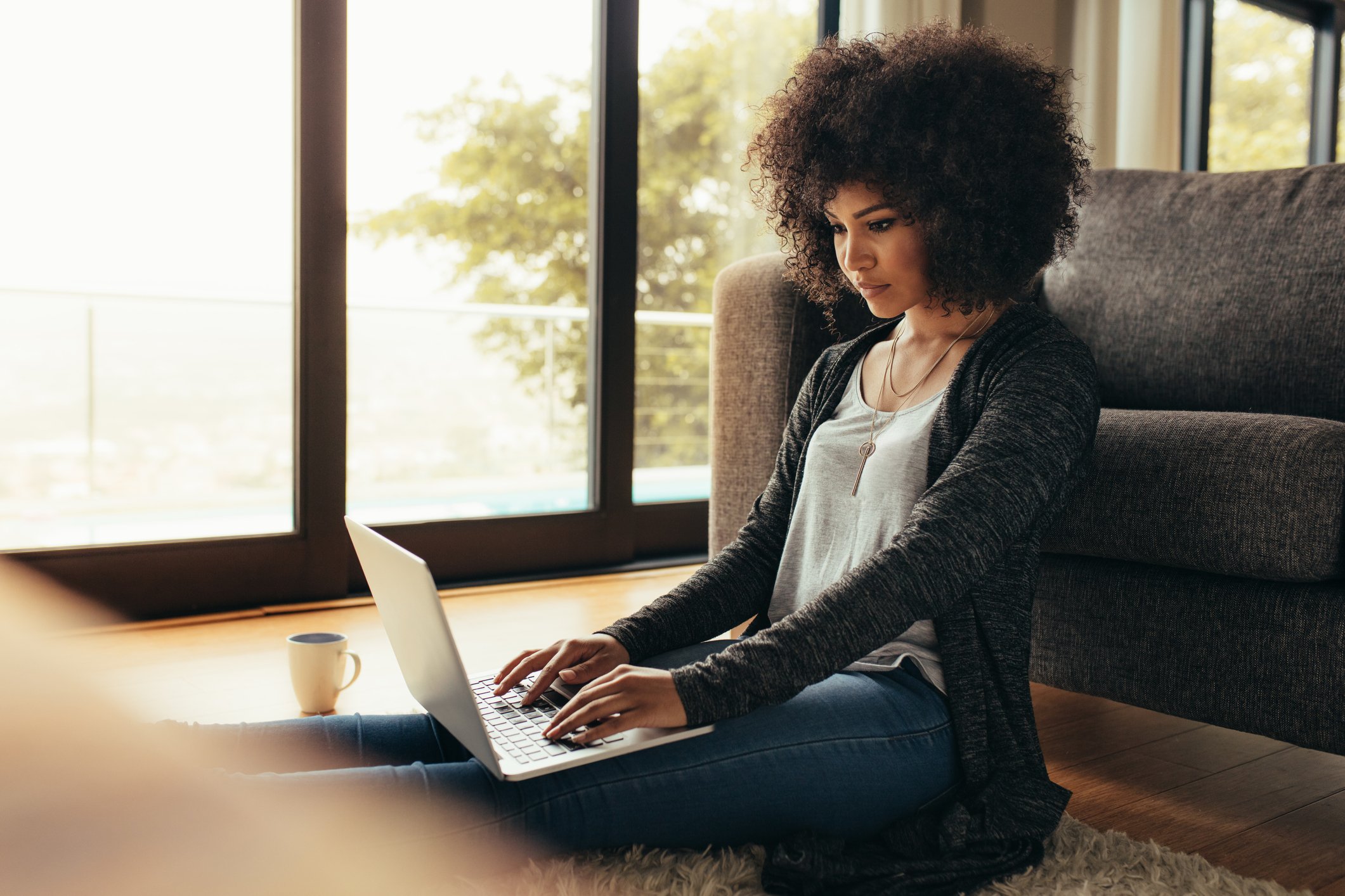 Person sitting on floor typing on laptop.