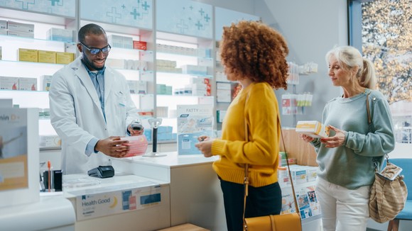A pharmacist serves customers at a pharmacy.