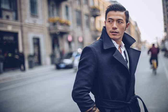 Businessperson dressed in fashionable trench coat on urban street.