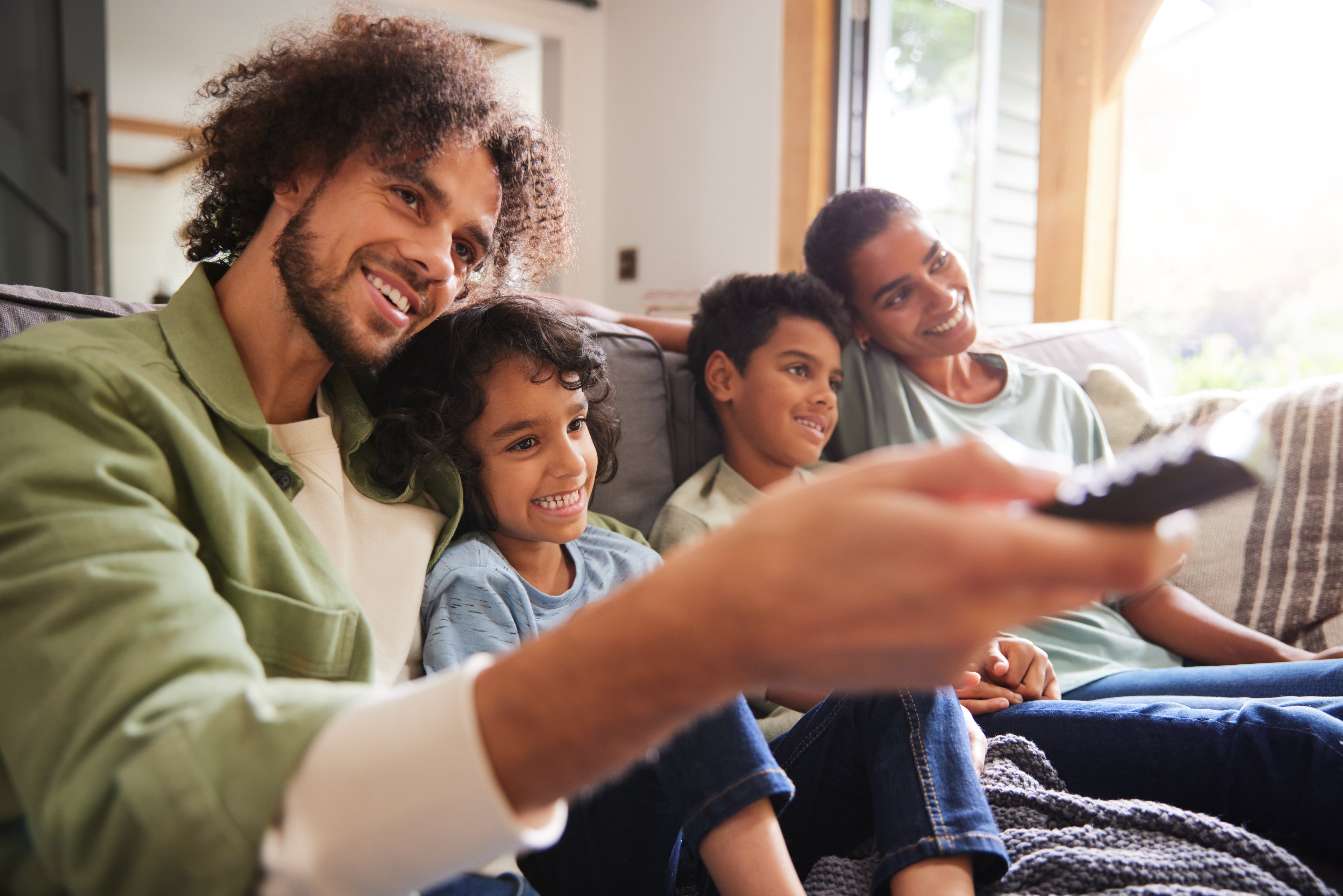 A family sits on a couch watching TV.