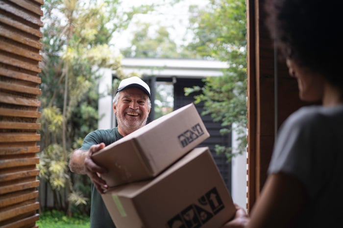 A delivery person holds two boxes.