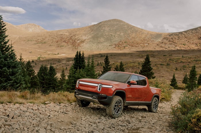 A Rivian RIT truck driving on a mountain path.