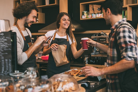 Baristas at coffeehouse serving coffee to customers.