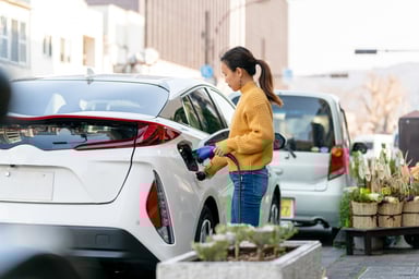 Person charging white electric vehicle.