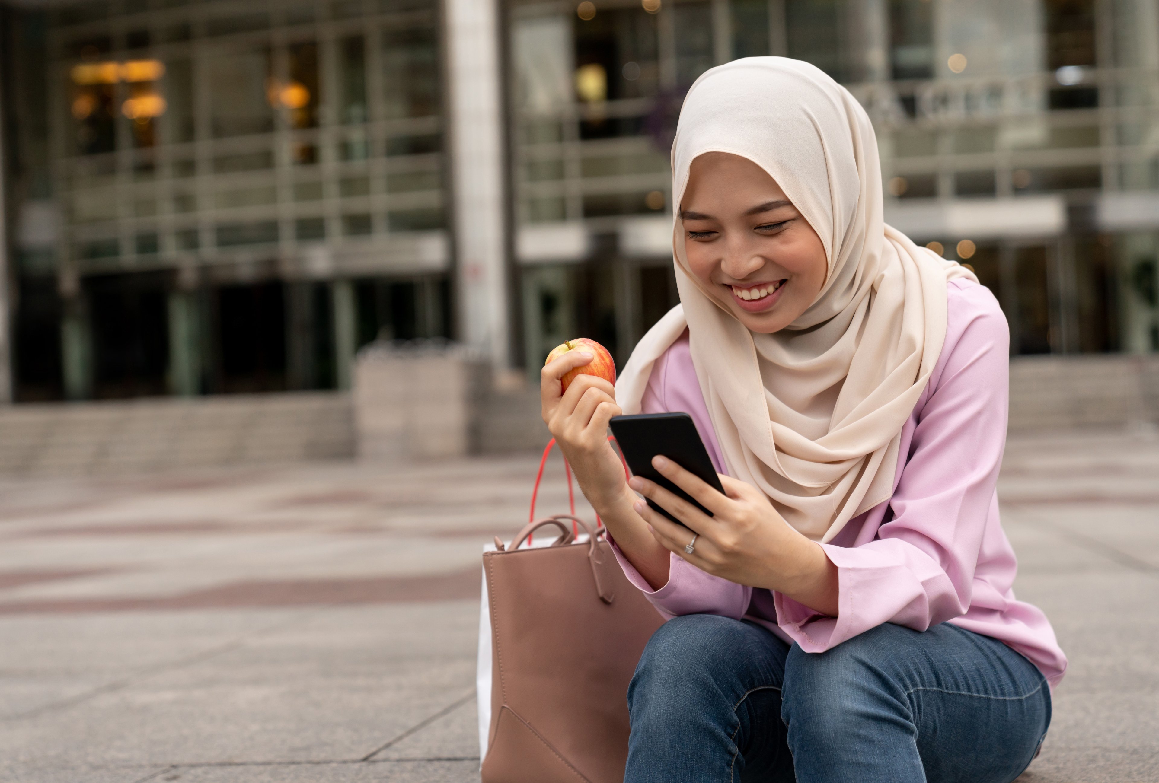 Person smiling at phone while eating an apple.