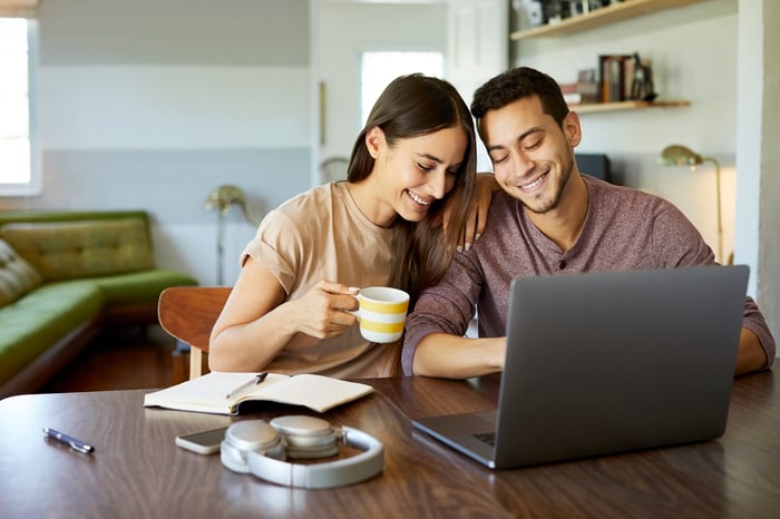 Two smiling people looking at a laptop.