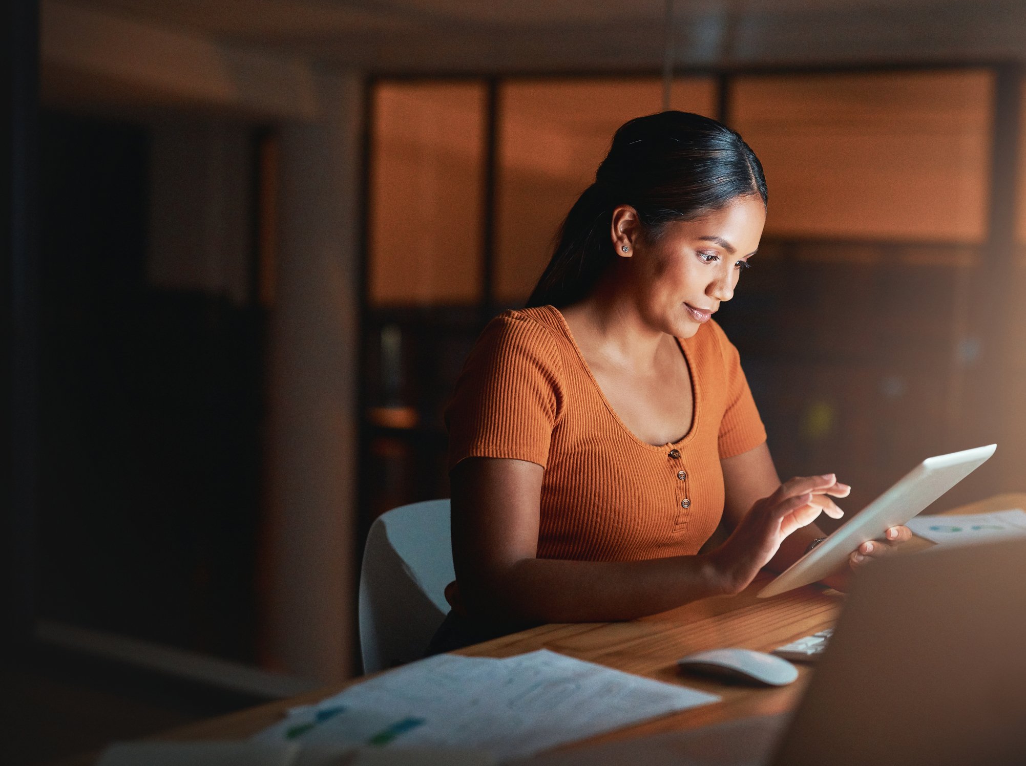 Person sitting at desk and using digital tablet in the dark.