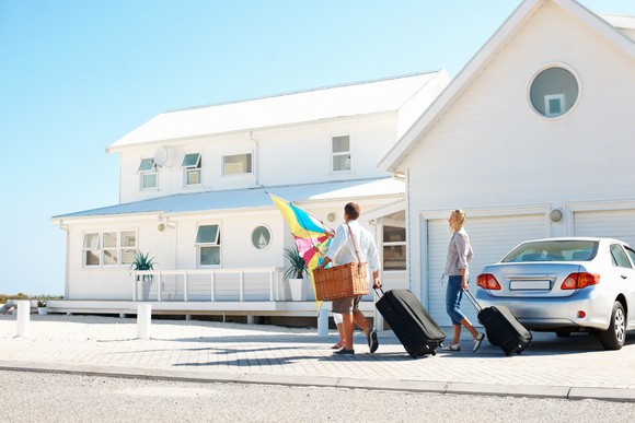 People with luggage arriving at two-story beach house.