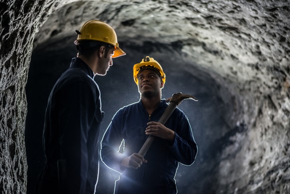 Two coal miners in a dark coal mine.