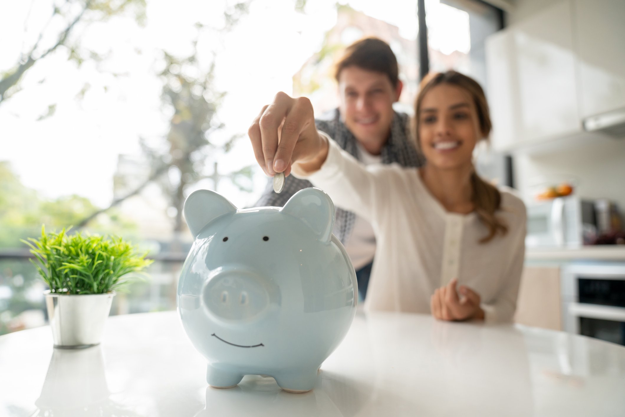 Two people putting coins in a piggy bank.
