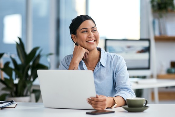 Person smiling behind a laptop.