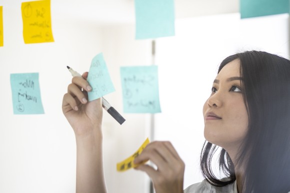 Office worker using sticky notes during a brainstorm.