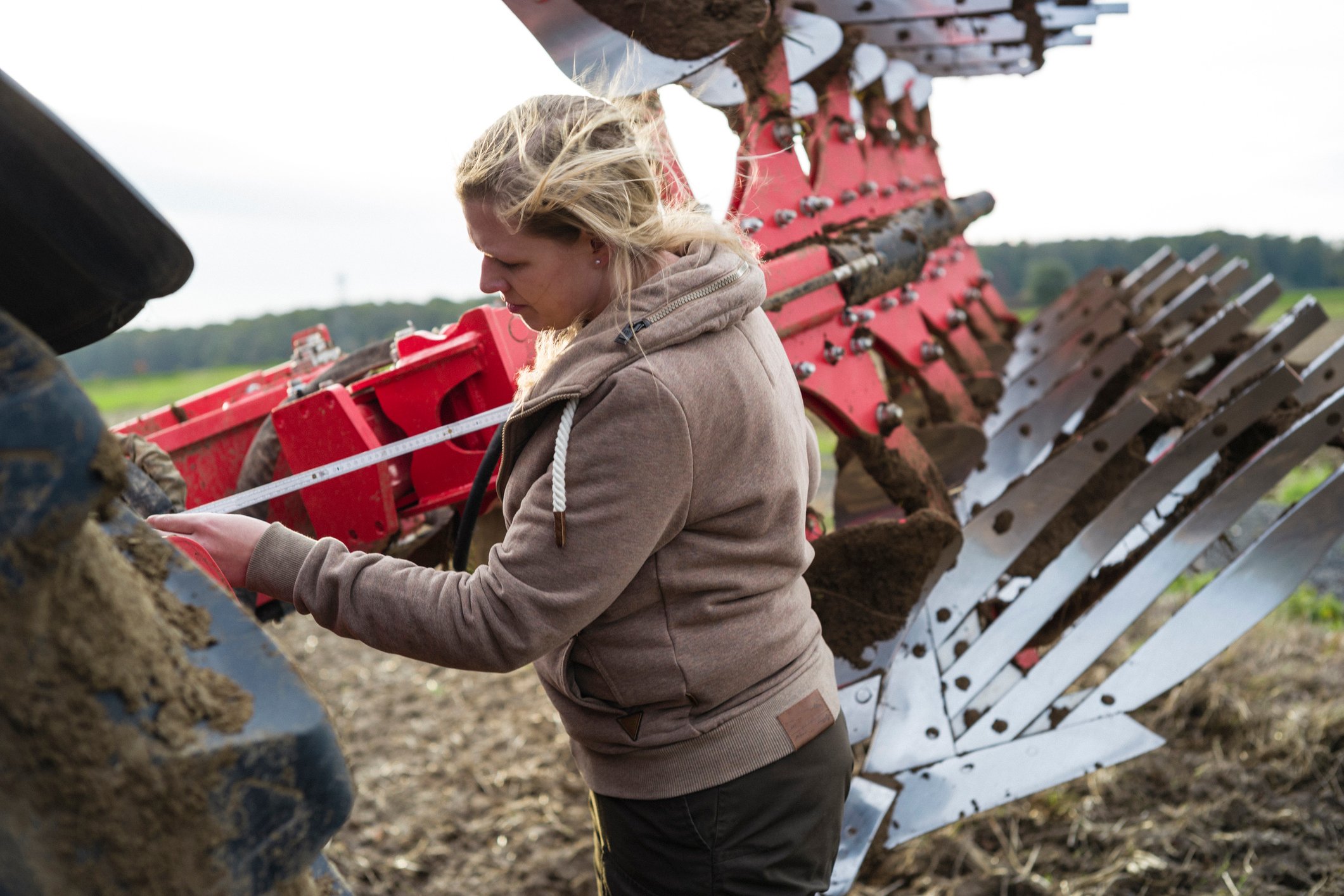 A farmer repairs a piece of farm equipment in an open field. 