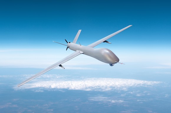 A military drone flying in blue skies.
