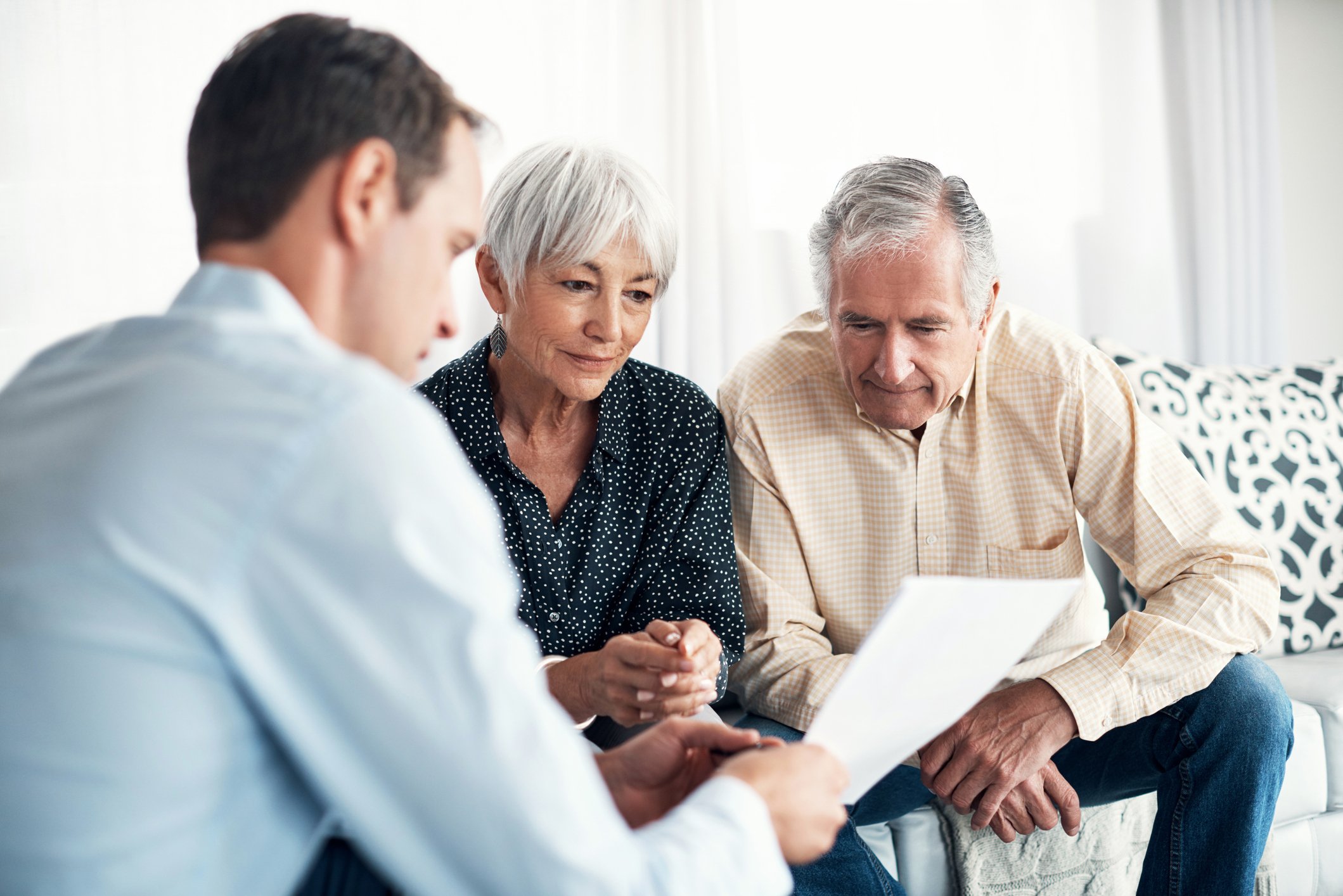 Three people review paperwork in a home environment.