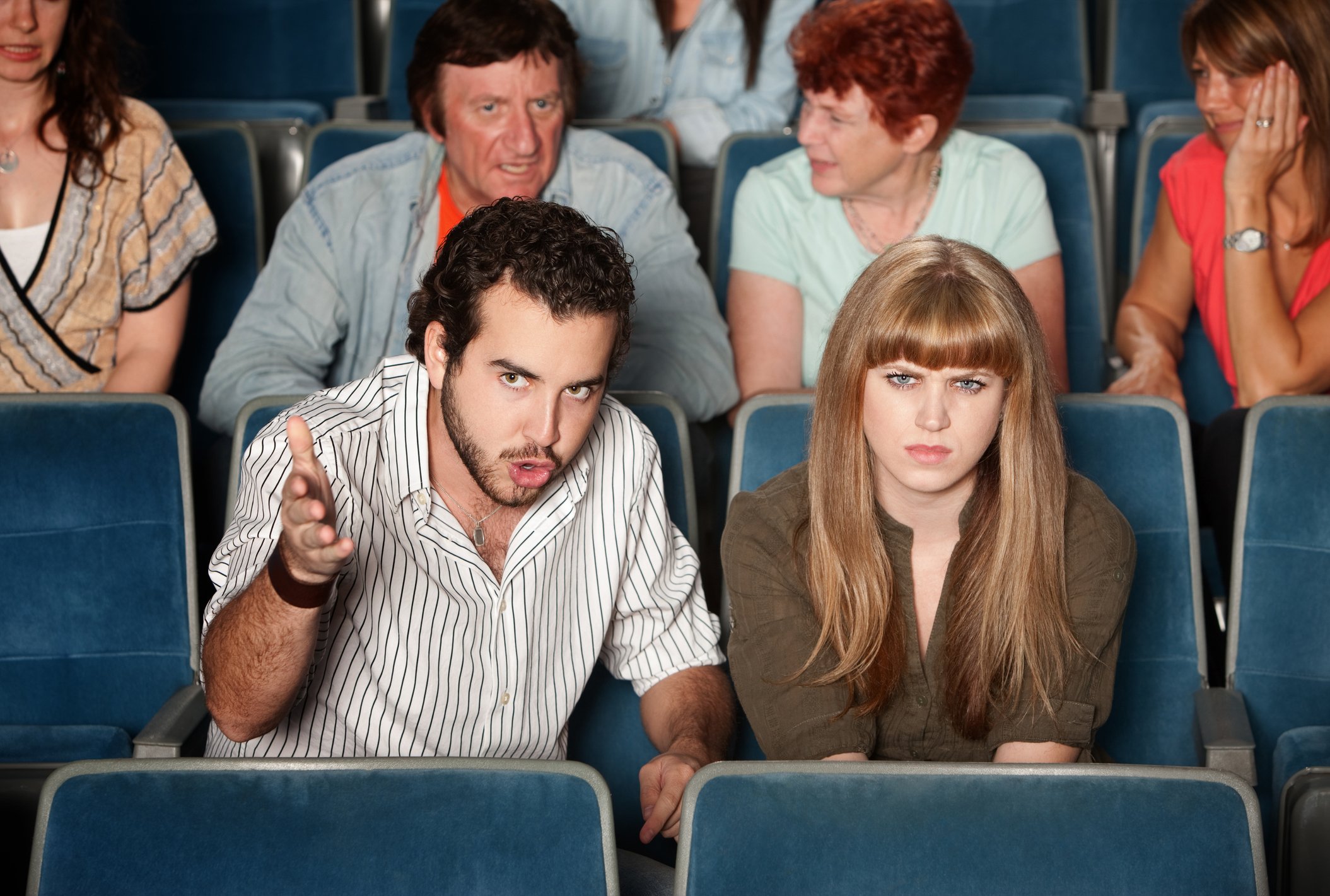 A group of frowning people in movie theater seats.
