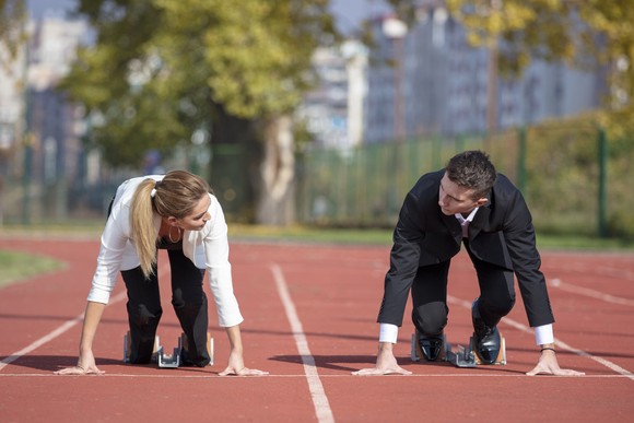 Two business people line up for a race on a running track.