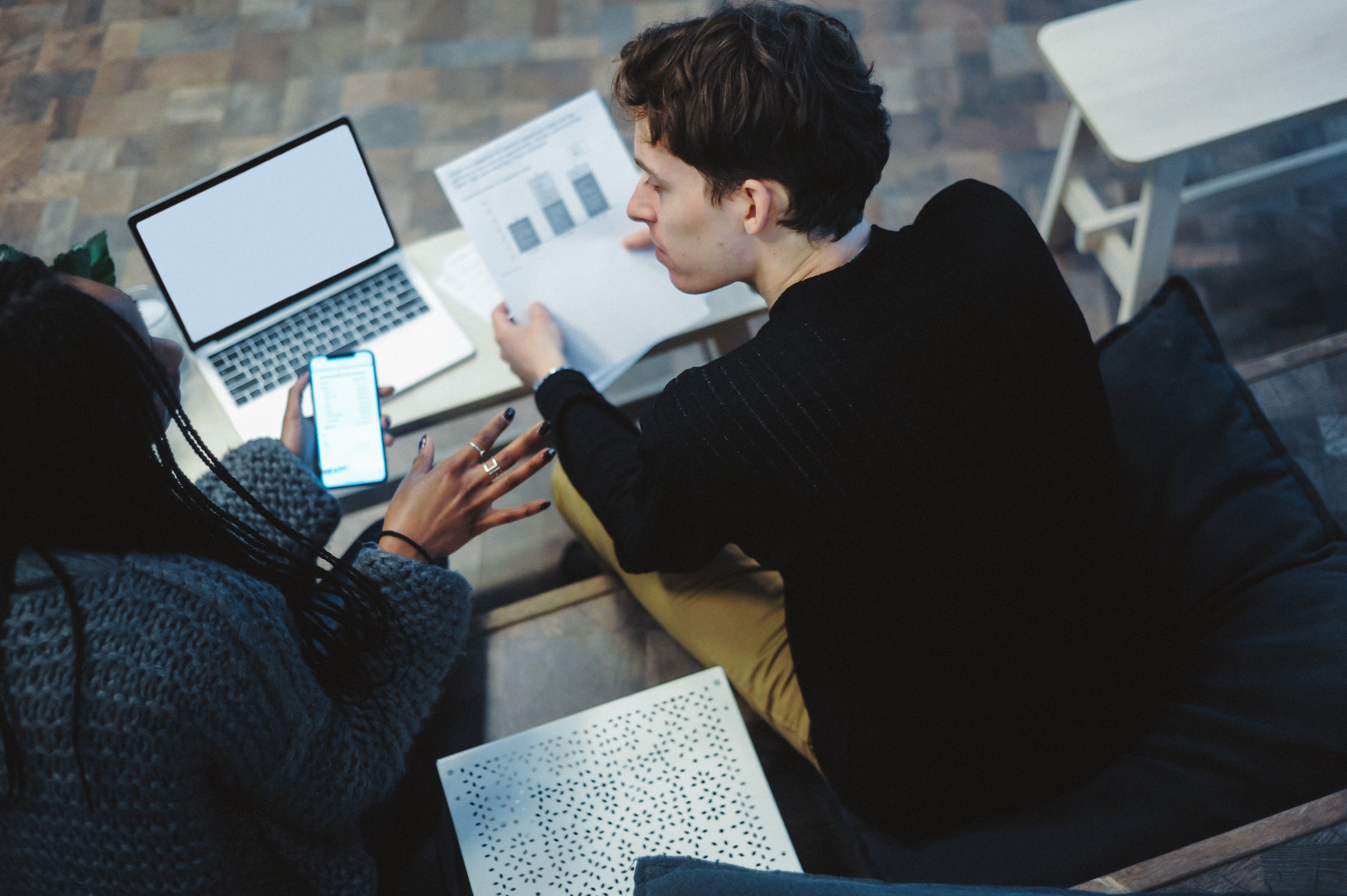 Two people discussing financial information while studying charts. 
