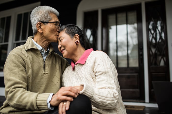 Two people embracing outside a house.