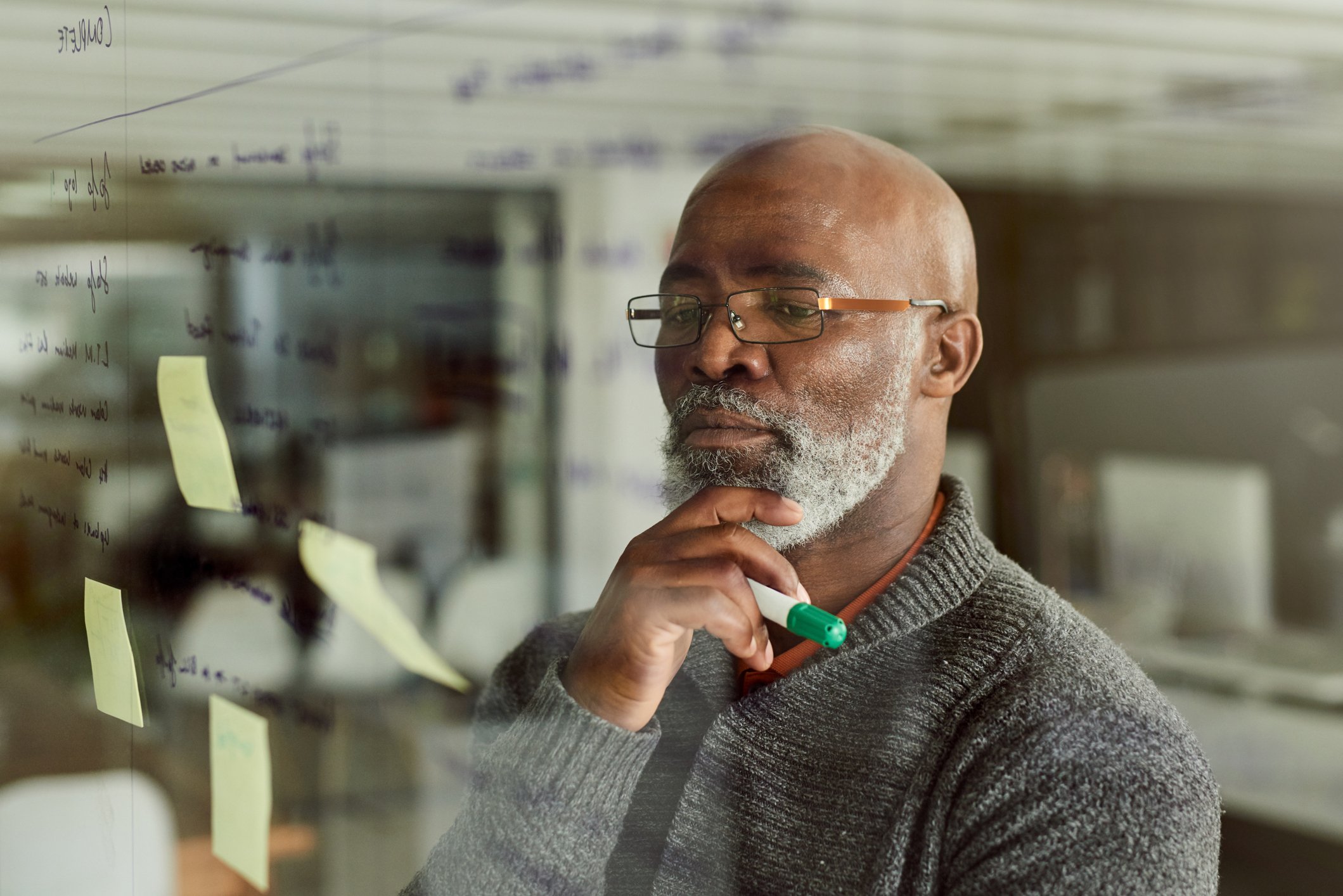 A person looking at a glass wall that has sticky notes attached to it.