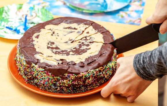 Person cutting slices out of a chocolate cake.