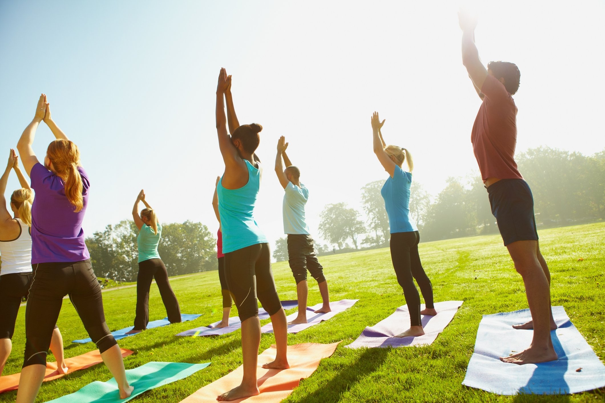 Group of people doing yoga in a park-like setting.