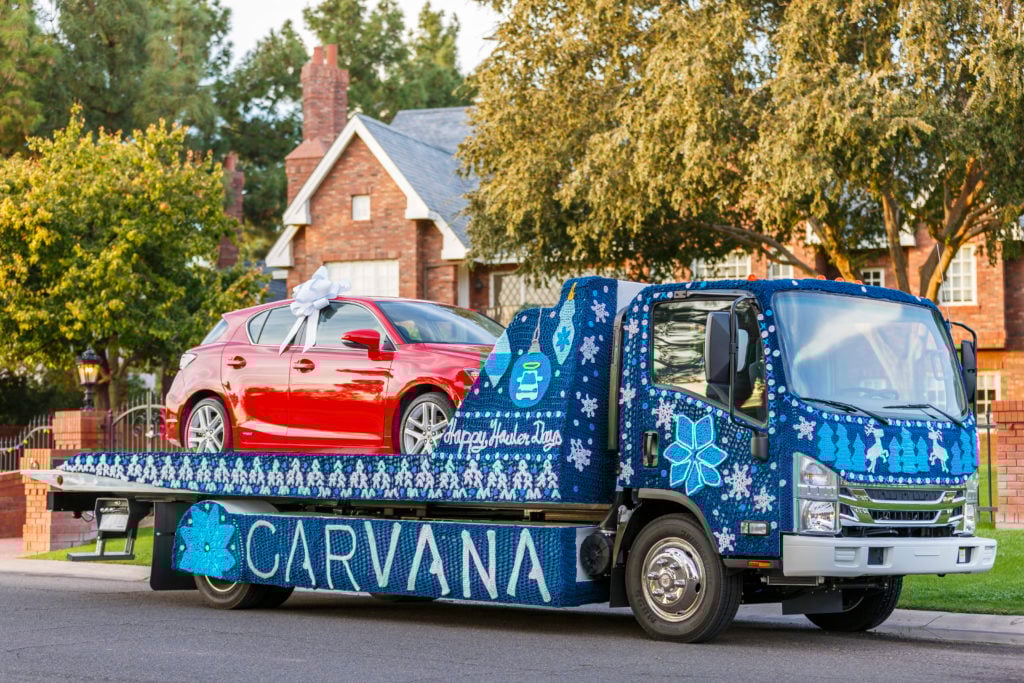 Carvana flatbed delivering a vehicle.