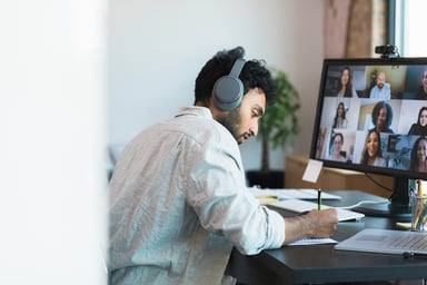 Man Taking Notes During Videoconferencing Meeting