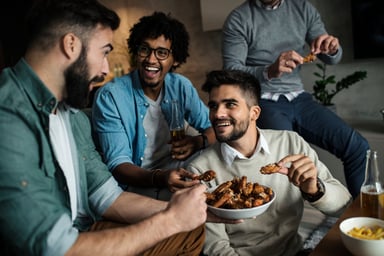 A group of people on a couch eating chicken wings