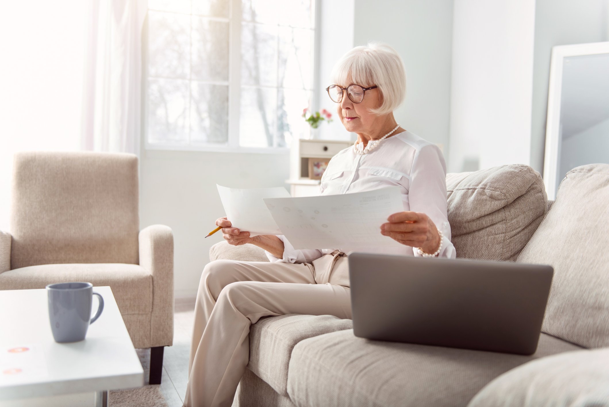 A person on their couch looking at papers.