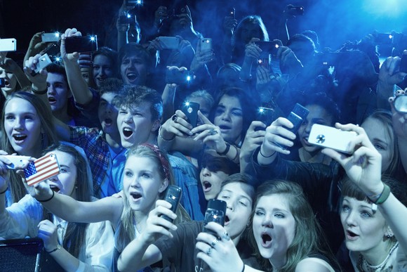 Fans taking pictures at a concert with their smartphones.