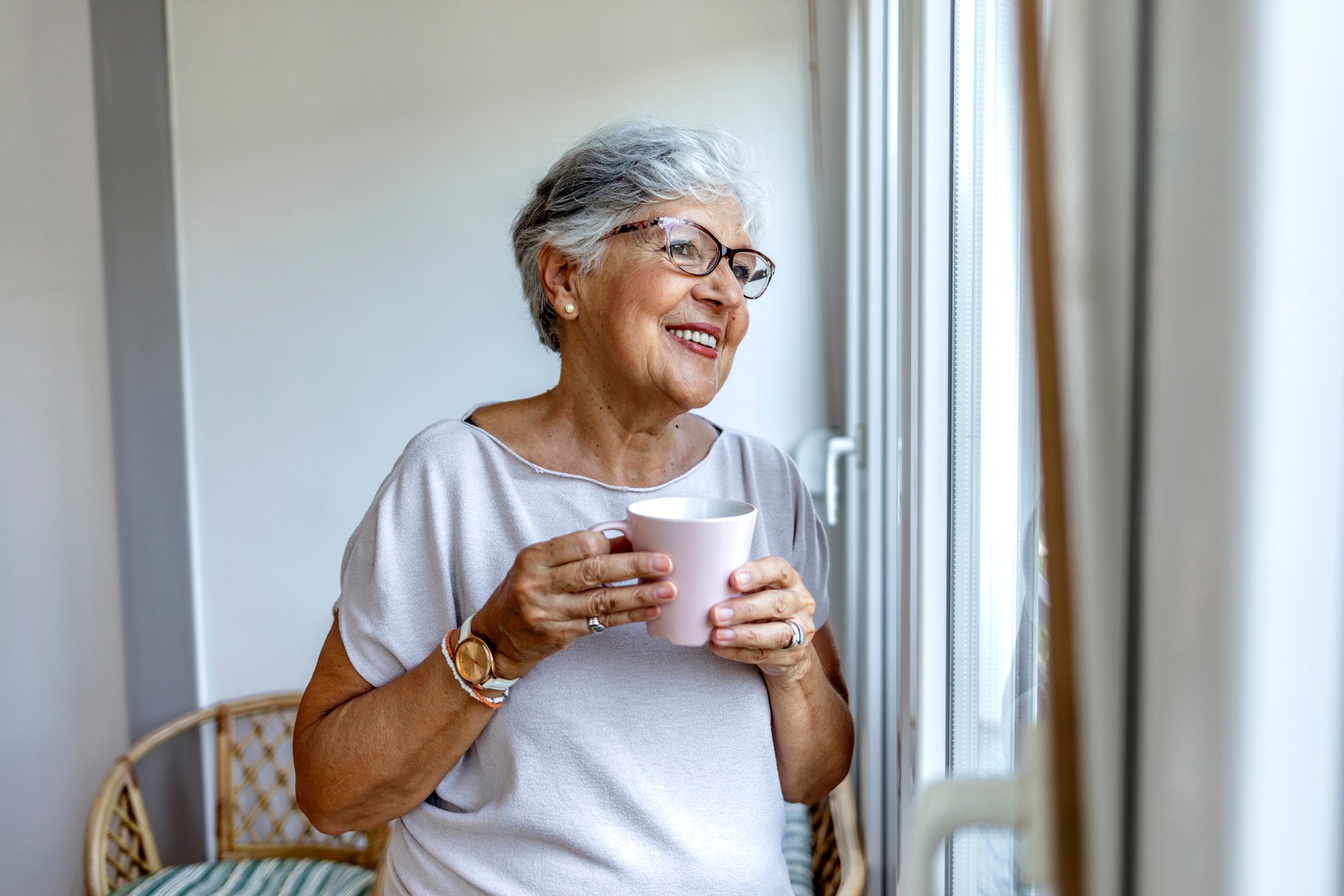 Person holding coffee cup and looking out the window.