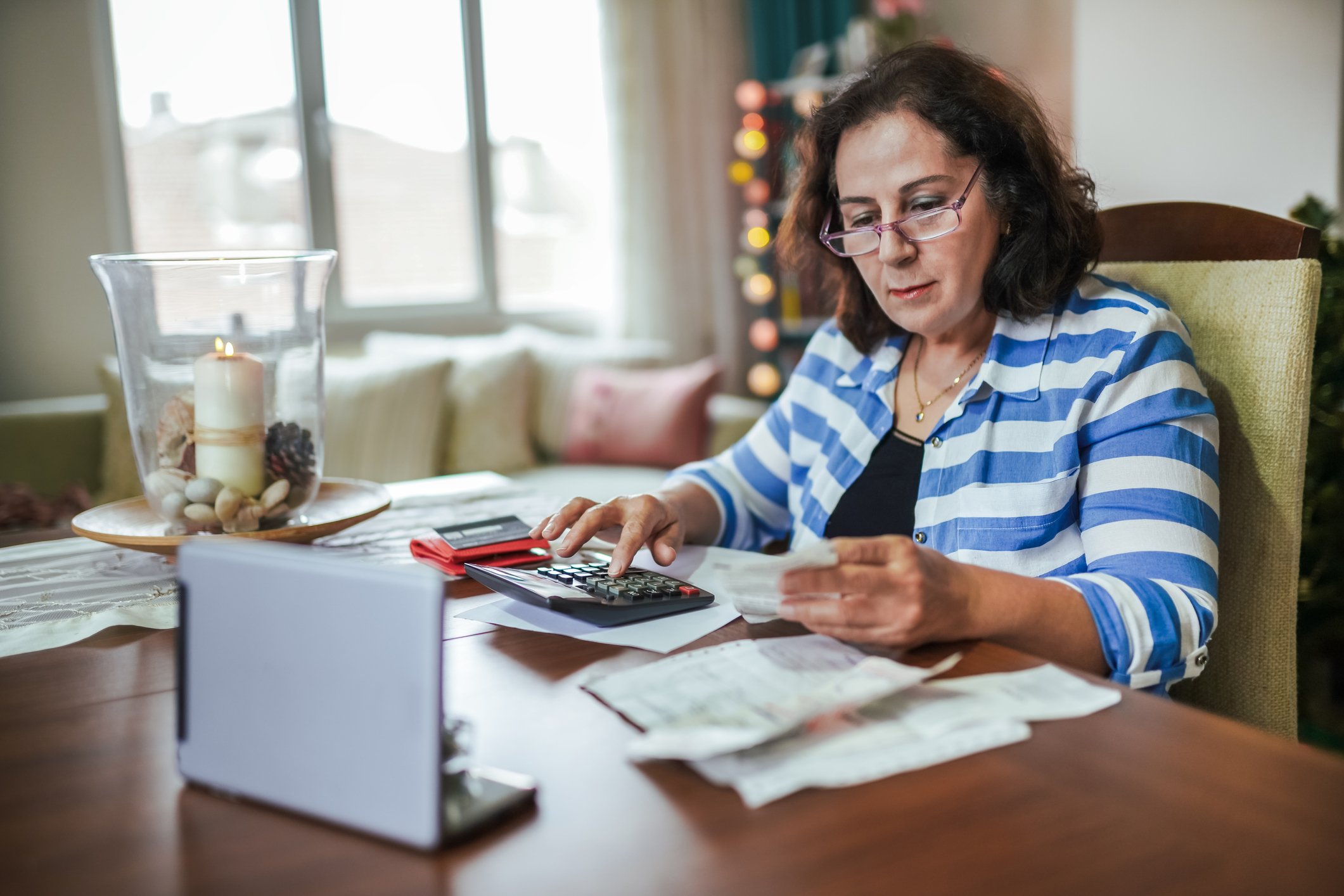 Person sitting at desk with calculator, tablet, and papers.