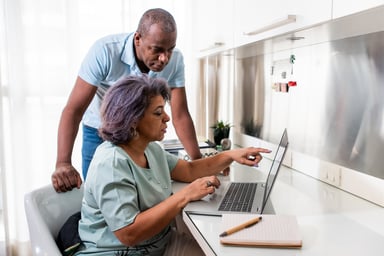 two people at a desk using a laptop